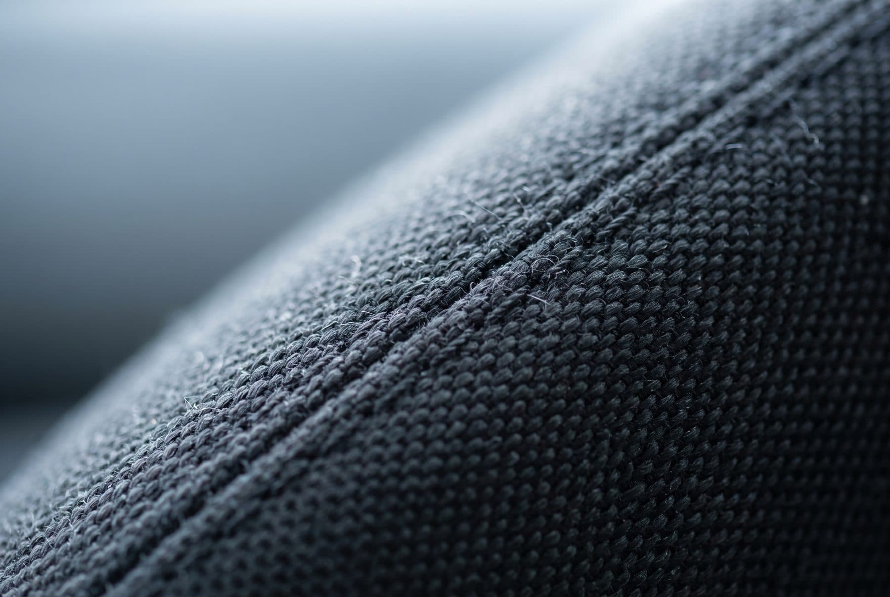 Detailopname van schone, donkergrijze autobekleding met een strakke stiknaad.