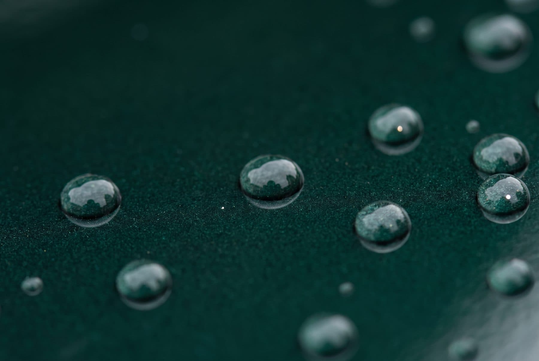 Waterdruppels die strak opparelen op diepgroene gecoate autolak.